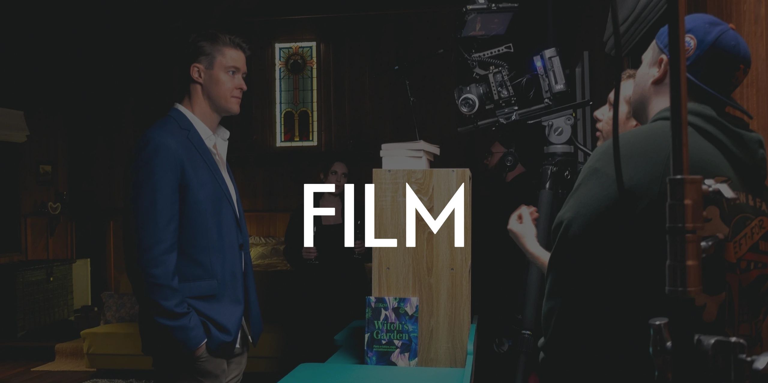 Film crew recording a scene with an actor in a blue suit.