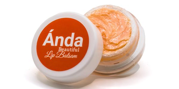 Open container of Ánda Beautiful Lip Balsam with orange balm inside.