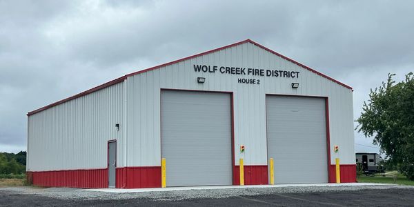 Fire station building with closed garage doors under cloudy sky.