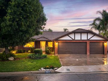 Suburban house with a lit garage at dusk.