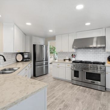 Modern white kitchen with stainless steel appliances.