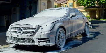 Luxury Mercedes-Benz covered in foam during mobile car wash service at residential home