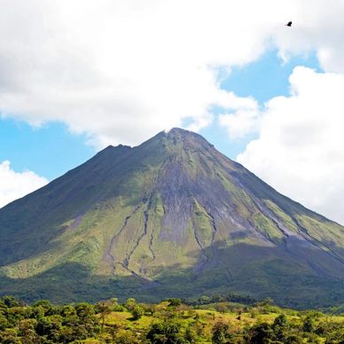 A majestic volcanic mountain under a partly cloudy sky.