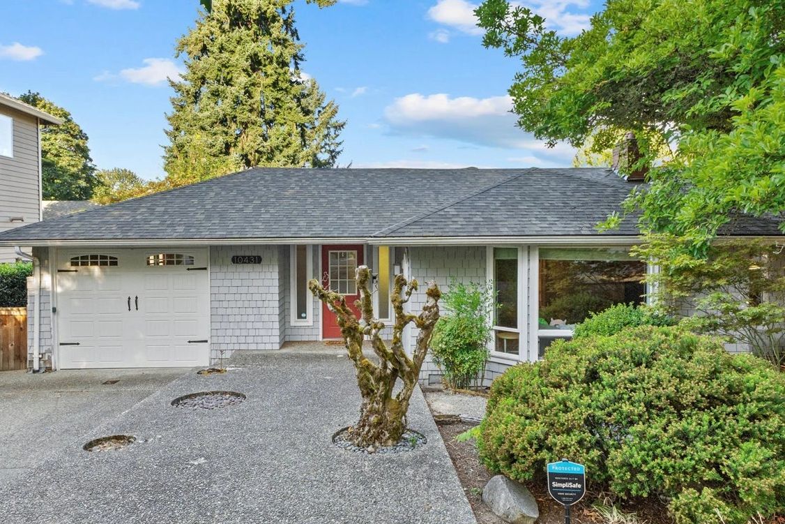 Single-story house with a gray roof, white garage door, and a red front door.