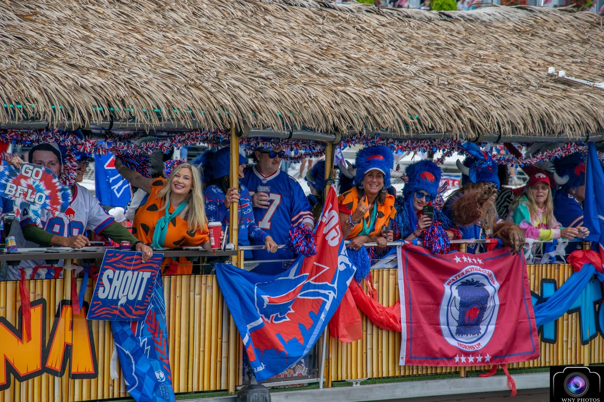 Buffalo Bills fans dressed in vibrant costumes on a tiki-style parade float.