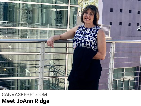 Woman with medium length brown hair, blue and white pattern shirt and blue suite leans on a railing.