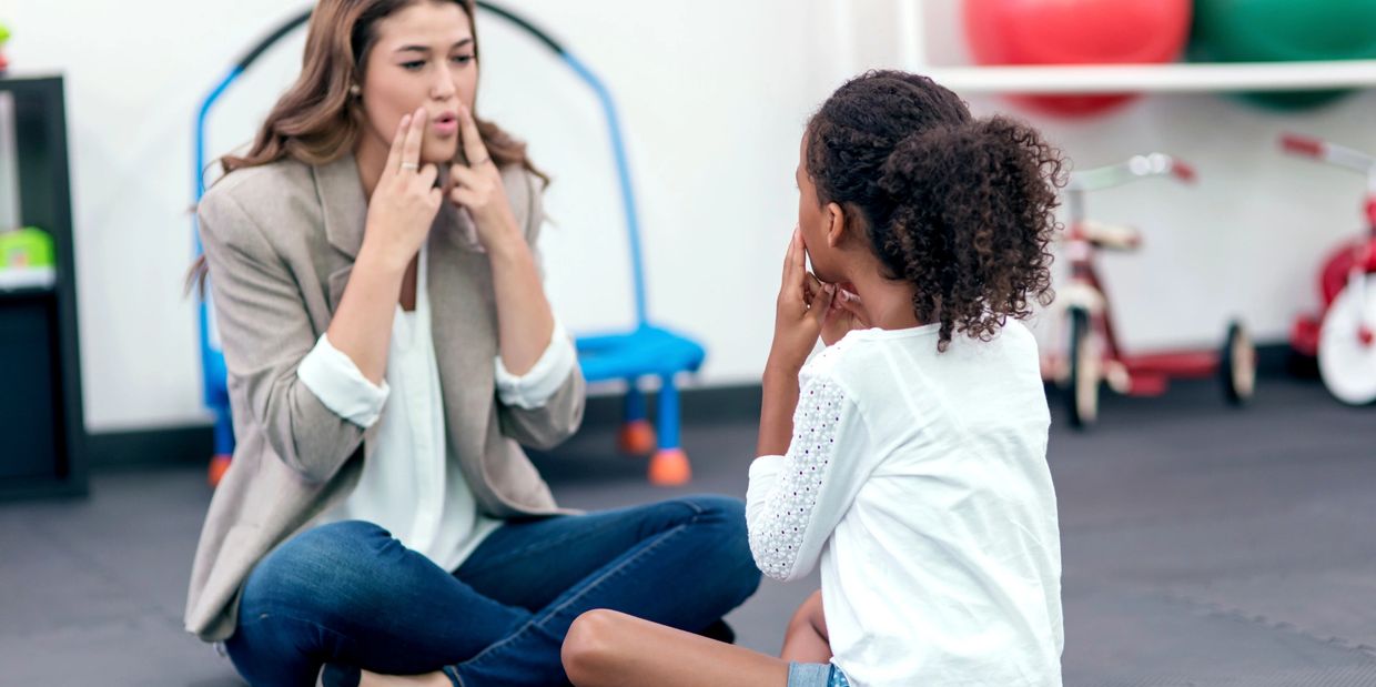 Pediatric Speech Language Therapist pointing to mouth for speech sounds with pediatric patient