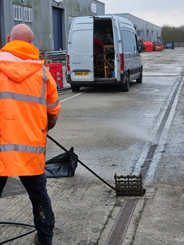 Using high pressure water jetting equipment, to remove silt build-up from a surface water drainage c