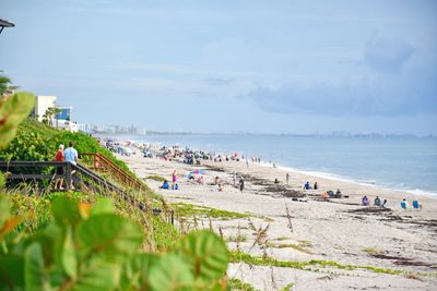 A sunny beach with people relaxing and enjoying the ocean view.