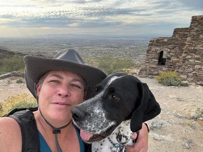 Person and dog posing at a scenic mountain spot.