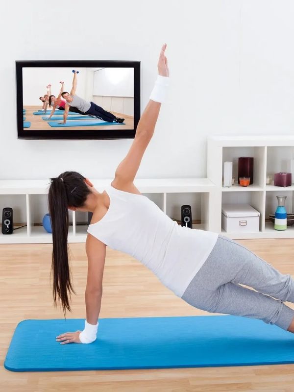 A lady doing a side plank while participating in a virtual exercise class.