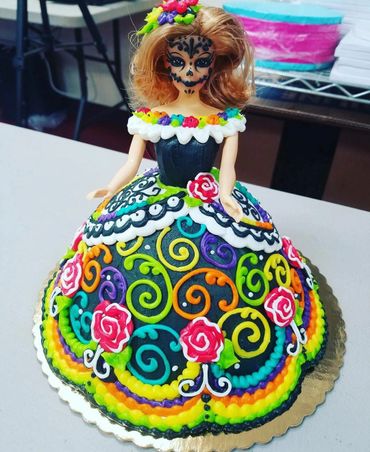 A black colored doll cake with colorful design