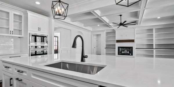 Modern white kitchen with large island and built-in shelves.