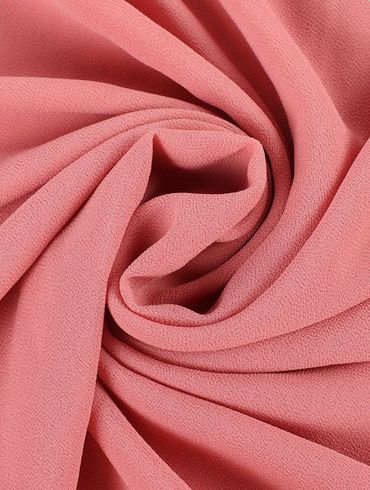 Close-up of soft pink fabric twisted in a swirl pattern.