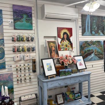 Art gallery corner with paintings and framed art on a blue table.