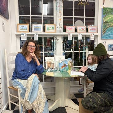 Woman and man with child at a cozy book and art display table.