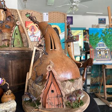 Artistic gourd sculptures with whimsical house designs and metal wire accents.