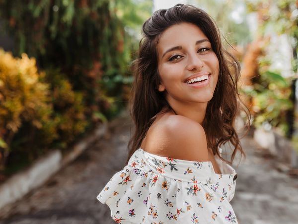 woman with wavy hair smiles widely at camera