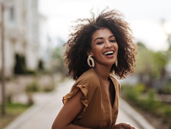 Woman with coily hair smiles widely