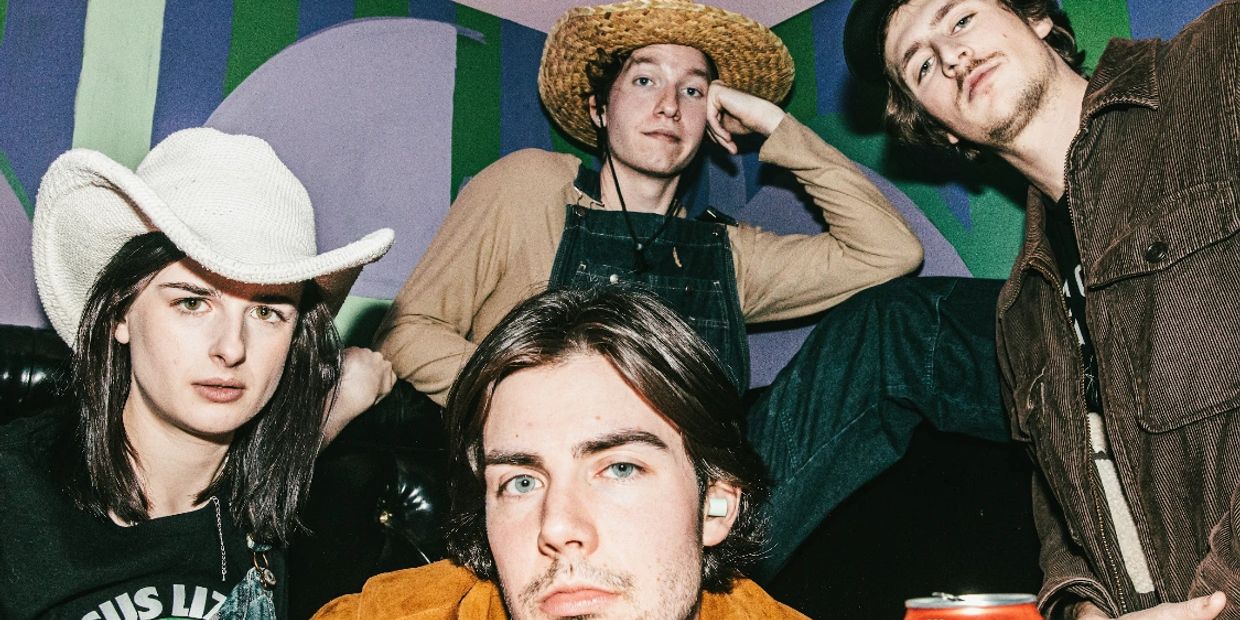 Four people posing with hats in a colorful room.