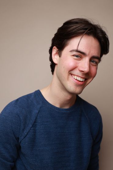 Smiling young man in a blue sweater.