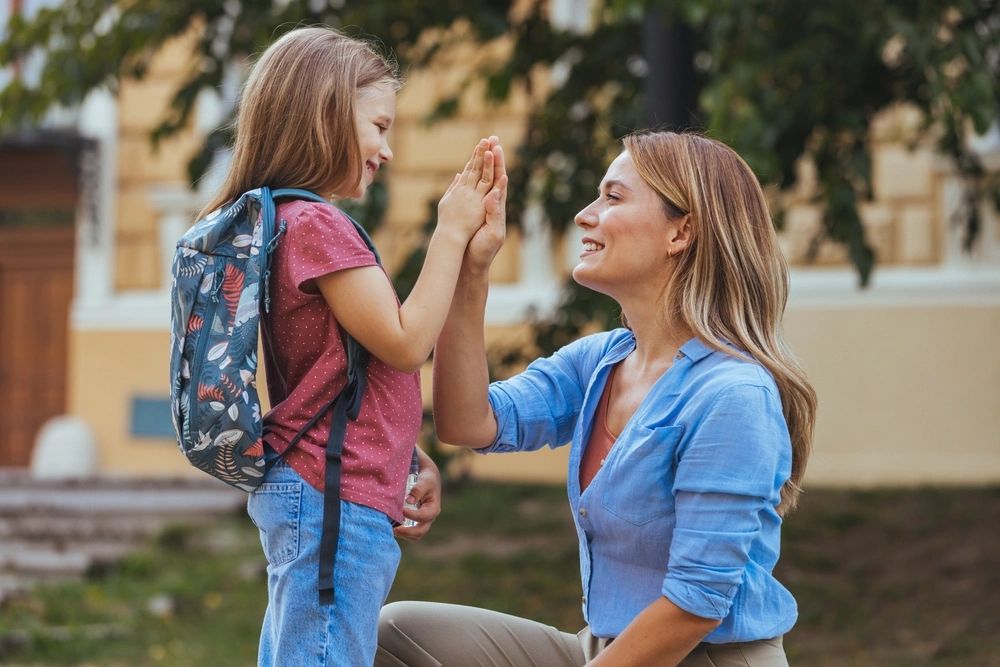 A parent and child greeting one another at school drop-off