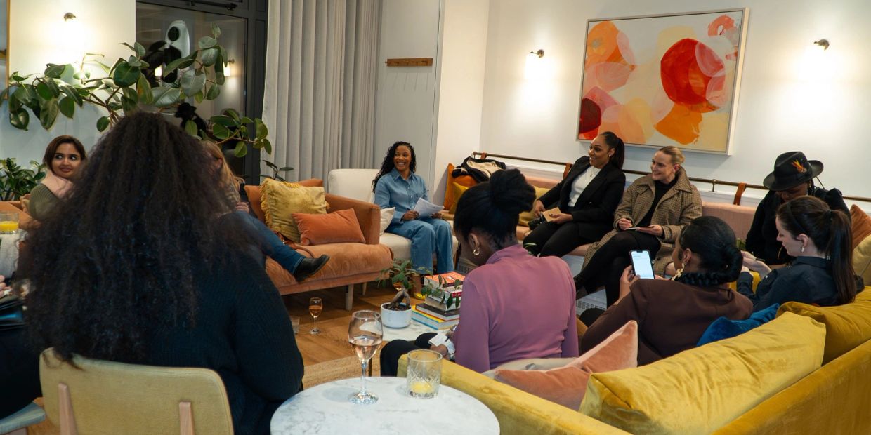 A group of diverse women gathered in a cozy living room for a meeting or discussion.