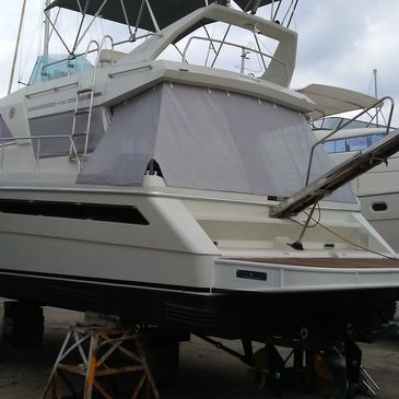 A white yacht on stands at a dock, covered with a protective sheet.