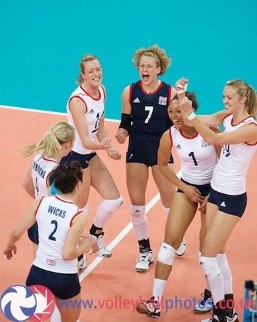 Female volleyball team celebrating a point on the court.