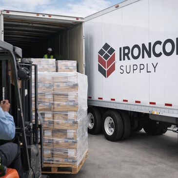 Worker loading pallets into an Ironcore Supply truck using a forklift.