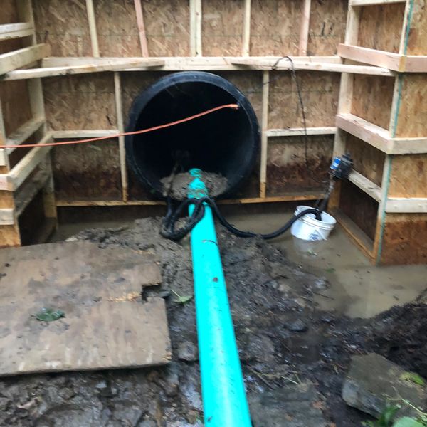 Divert steady creek water inside a new 36” pipe underneath driveway and wood forms to pour solid con
