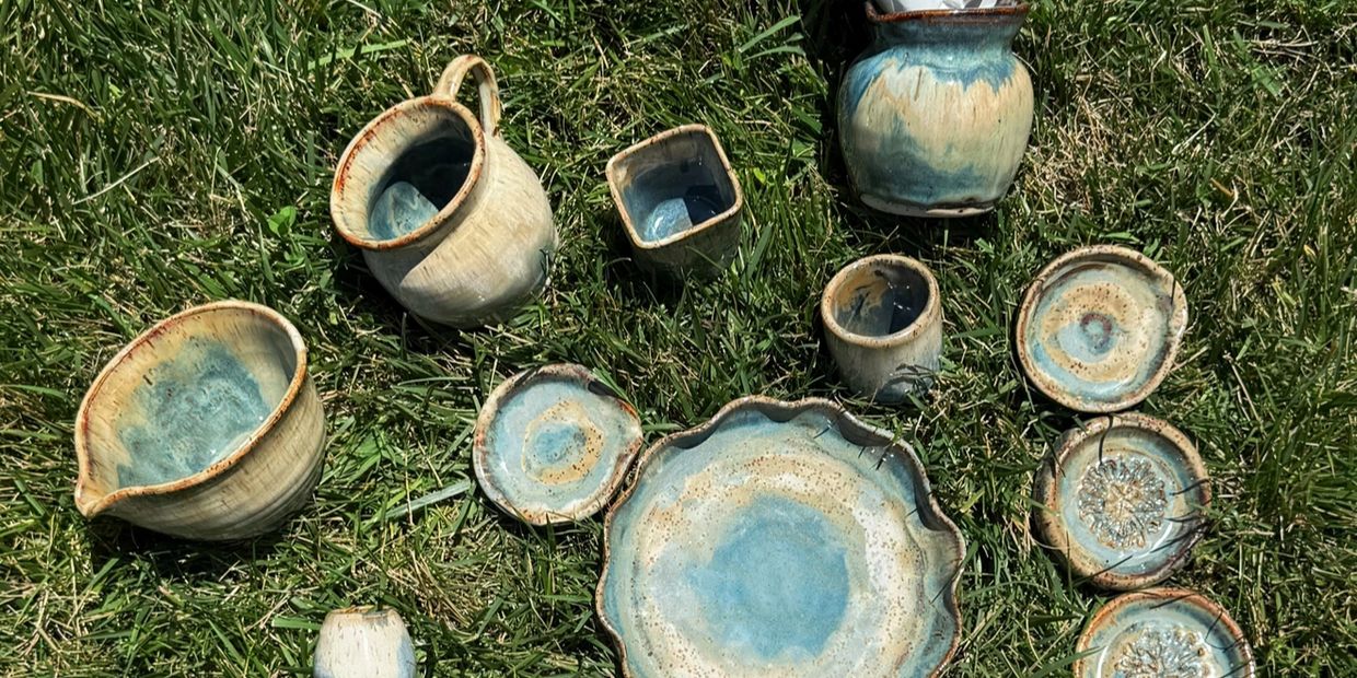 Handcrafted ceramic dishware set on grass.