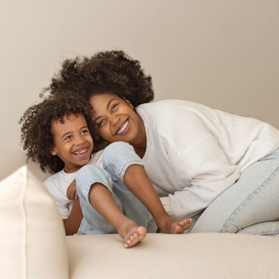 A joyful mother and child laughing together on a cozy couch.