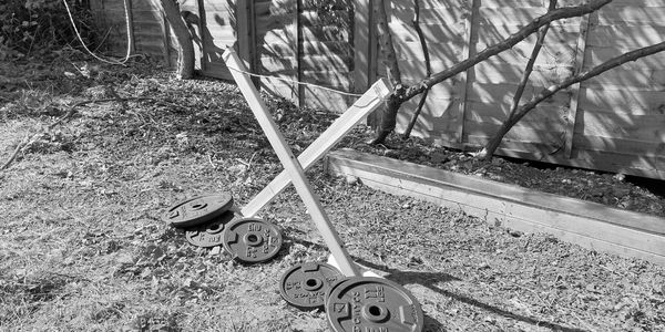 Pesi da palestra appoggiati su una base di legno in un giardino.