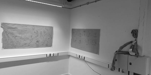 Angolo di una stanza con disegni su carta attaccata al muro.