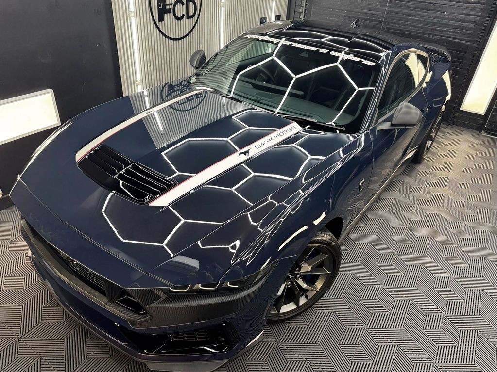 Shiny dark blue sports car with "Dark Horse" decal on hood in a showroom.