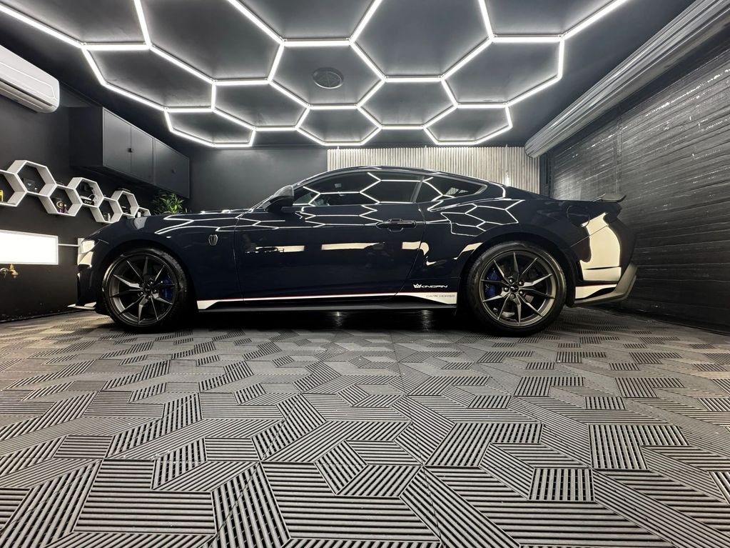 Sleek black sports car in a modern garage with geometric patterns and lighting.