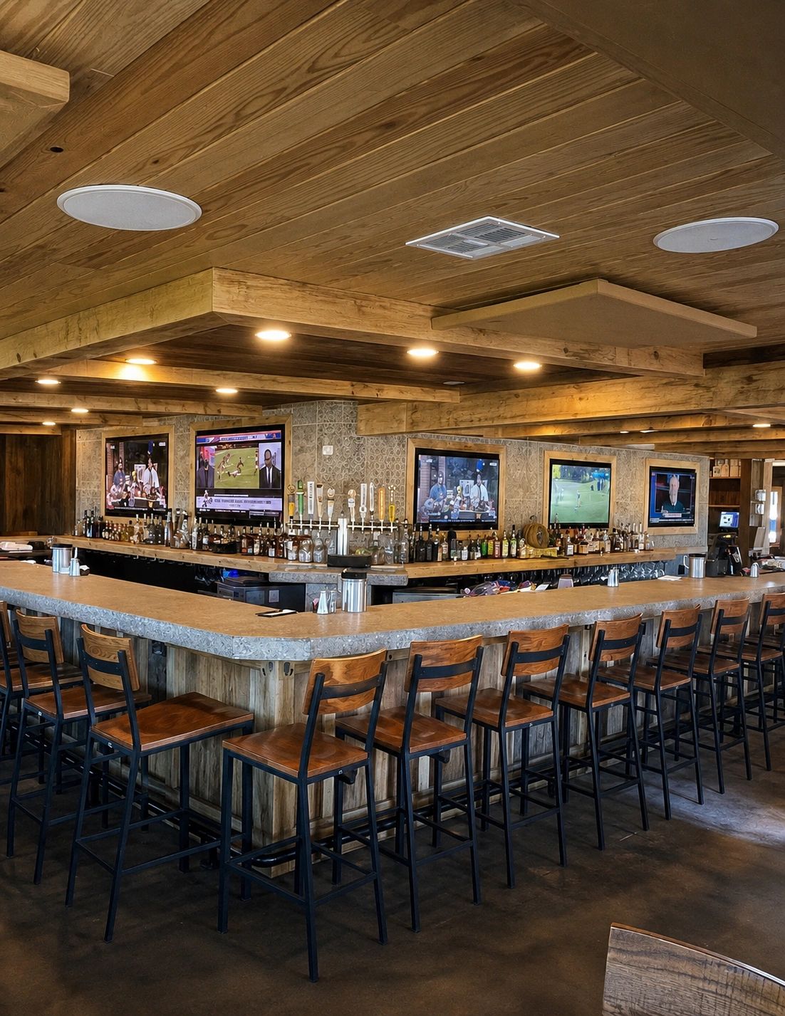 Rustic bar with wooden chairs and multiple TVs showing sports.
