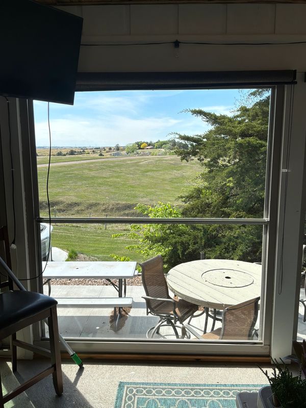 View of a grassy field and outdoor seating through a large window.