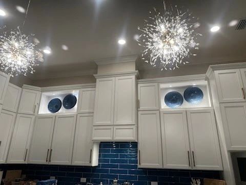 Decorative kitchen chandeliers installed above custom cabinets by Yeah, We Do That.