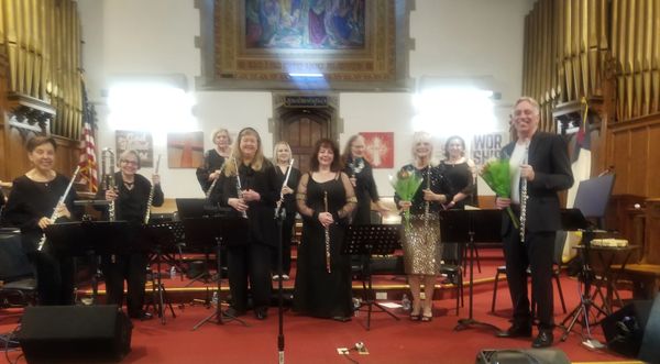 Group of musicians holding flutes on stage in a church.