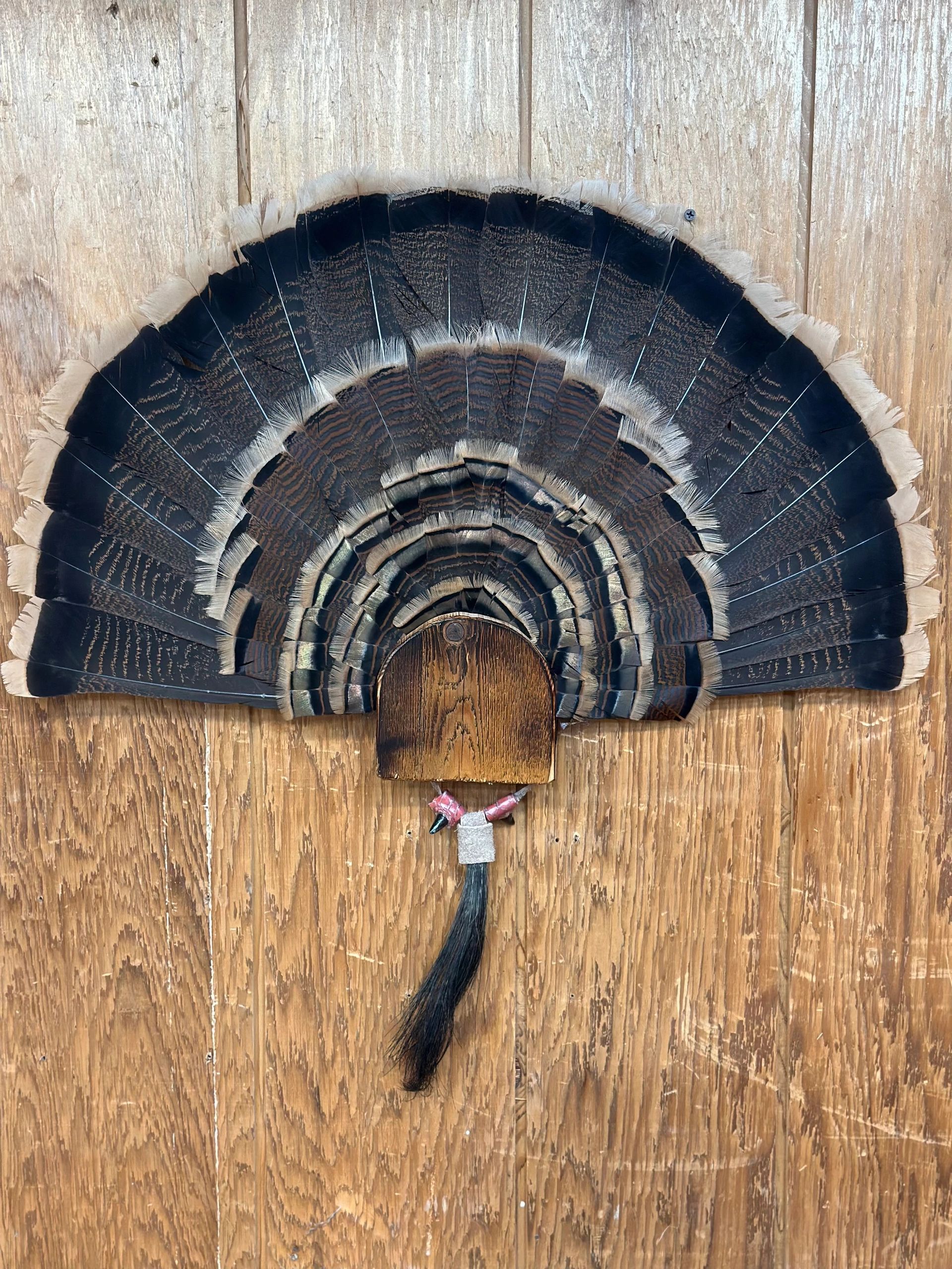 Decorative fan made of dark feathers displayed on wooden surface.