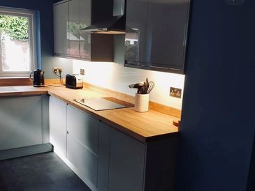 Modern kitchen with wooden countertops and grey cabinets illuminated by natural light.