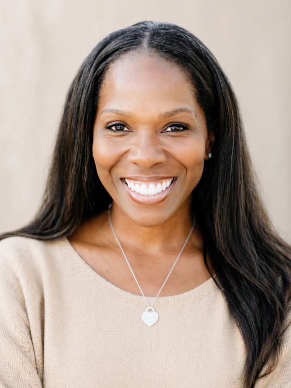 Smiling woman with long dark hair and a heart necklace.