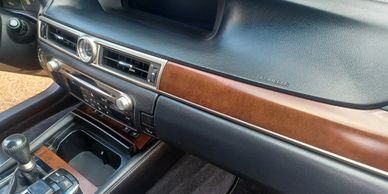 Car interior dashboard with wood trim and analog clock.