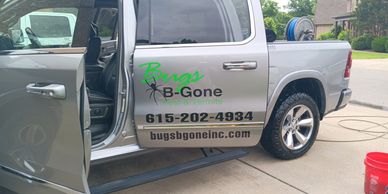 Silver pest control truck with Bugs B-Gone branding and open door.