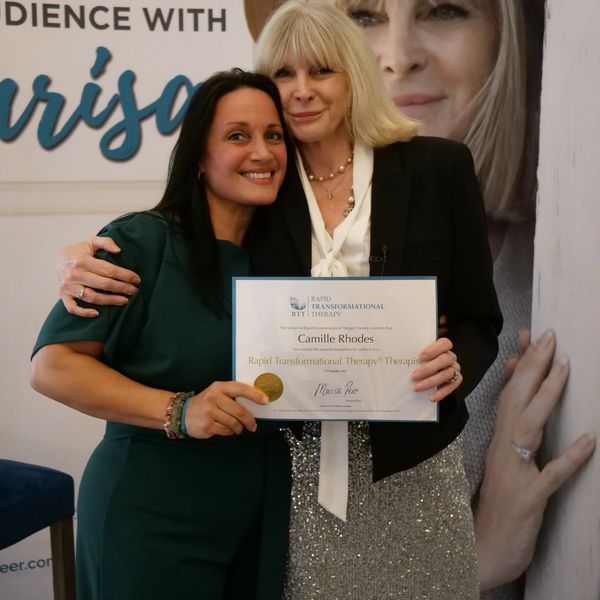 Two women smiling, holding a certificate for Rapid Transformational Therapy.