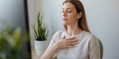 Woman practicing mindfulness with eyes closed and hand on chest.