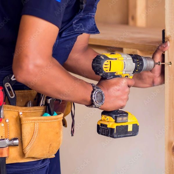 Handyman drilling a screw Into a board. 
