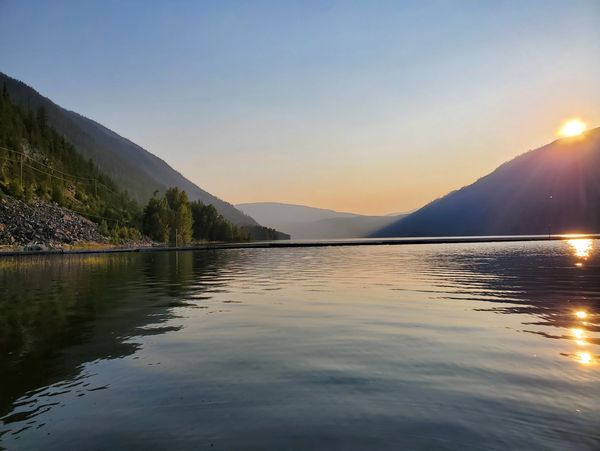 Sunset over a calm mountain lake with reflections on the water.